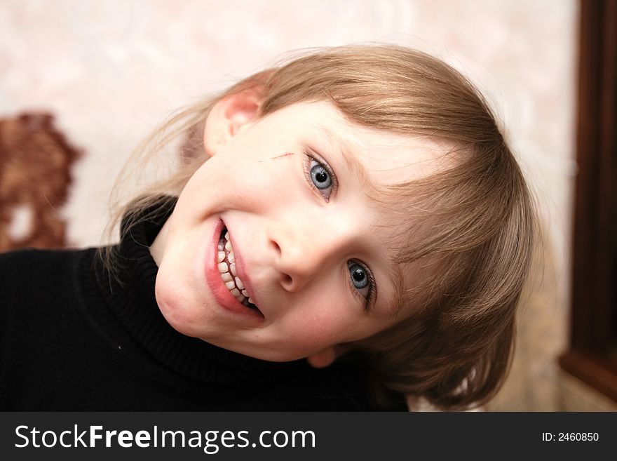 A smiling girl with blue eyes poses at home