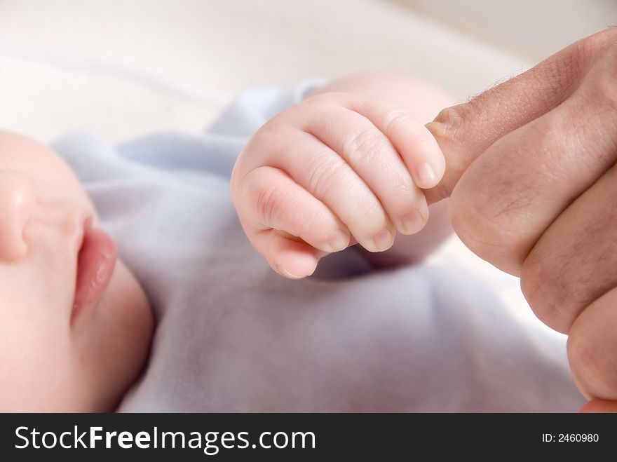 Small baby hand holding on to dad's finger