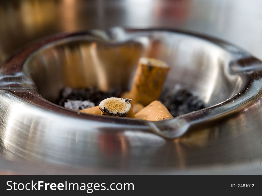 Close-up of an metal ashtray with squeezed cigarettes. Variation. Close-up of an metal ashtray with squeezed cigarettes. Variation