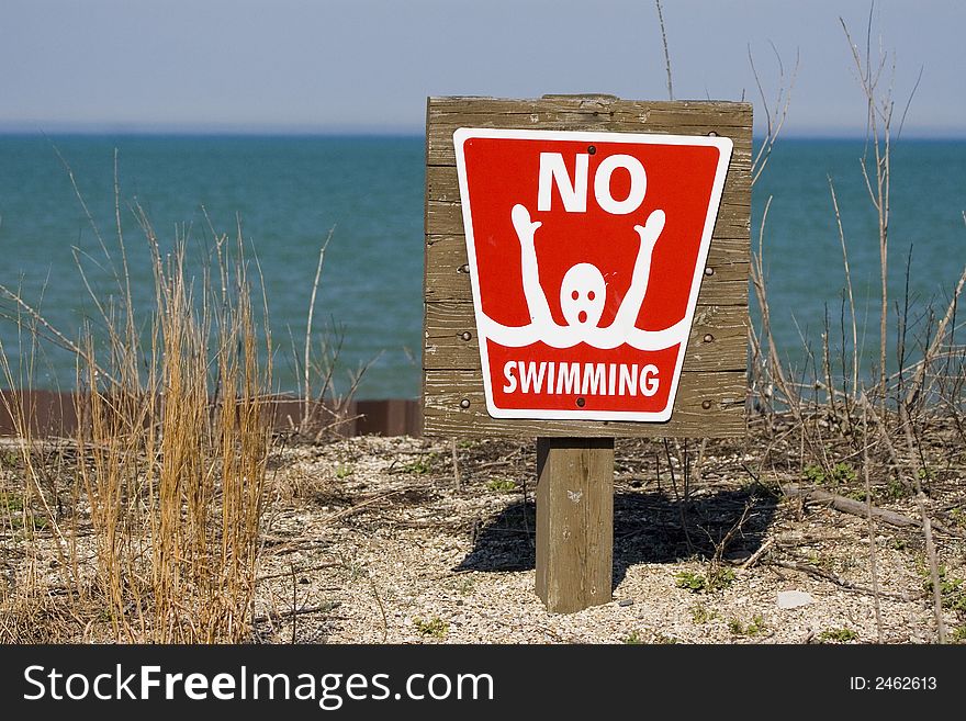 Red no swimming sign posted on beach