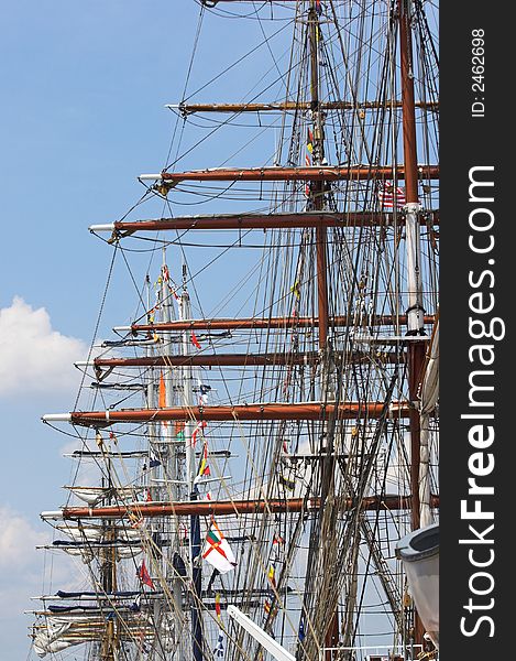 Row of masts and rigging of multiple tall sailing ships. Row of masts and rigging of multiple tall sailing ships