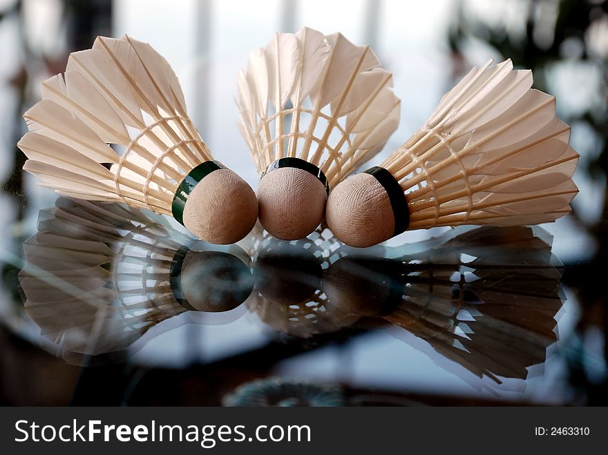 Three shuttlecock and shadow on the glass table