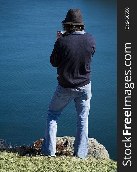 Young man videotapes his view of the ocean. Young man videotapes his view of the ocean