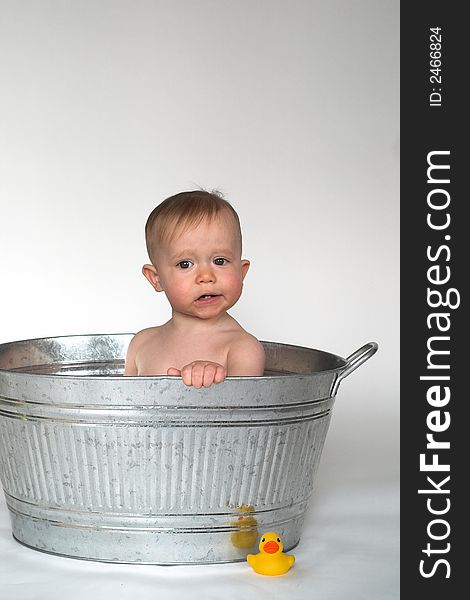 Image of cute baby sitting in a galvanized tub, with a rubber duck next to it. Image of cute baby sitting in a galvanized tub, with a rubber duck next to it