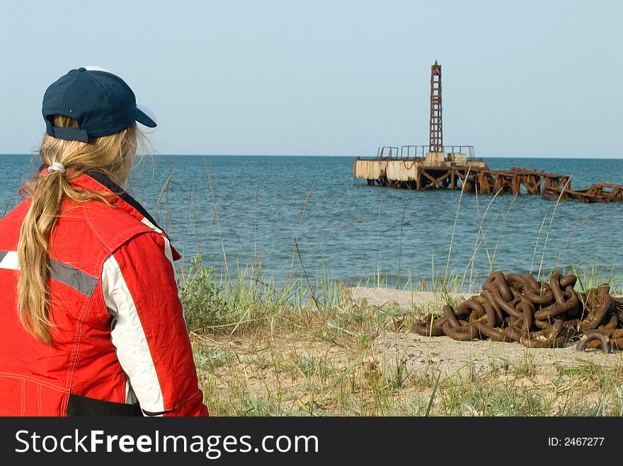 The girl looks at an old mooring in the sea. The girl looks at an old mooring in the sea