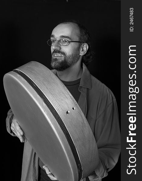 Portrait of man playing drum over black background