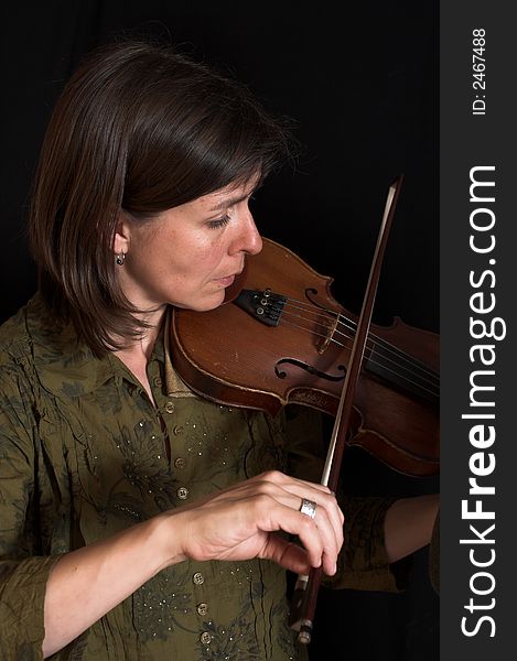 Mid-age woman playing violon over black background