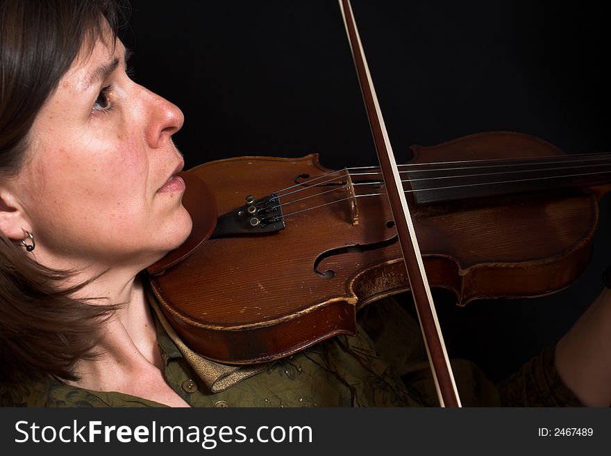 Mid-age woman playing violon over black background