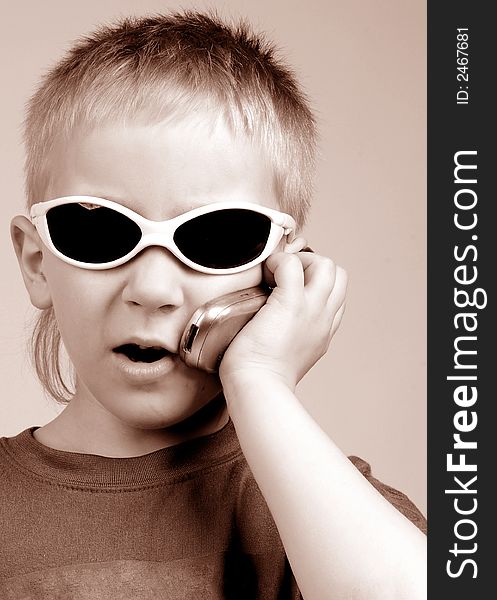 The boy talks by mobile phone on a brown background. The boy talks by mobile phone on a brown background