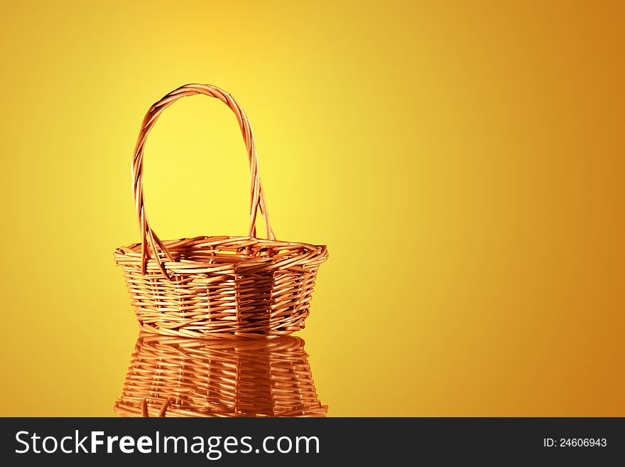 Empty wicker basket on nice yellow background with reflection