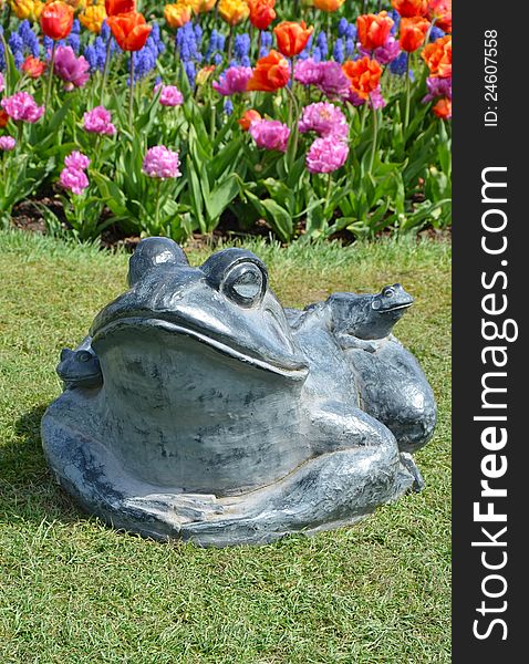 Stone frog in colorful spring garden