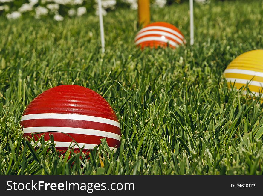 Three stripped croquet balls on green grass background