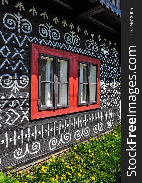 Colorful red windows on traditional Slovak wooden cottage
