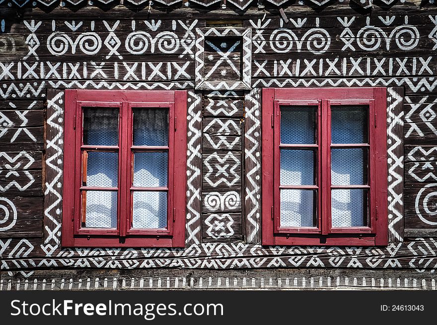 Red windows on wooden wall of traditional cottage, Cicmany, Slovakia