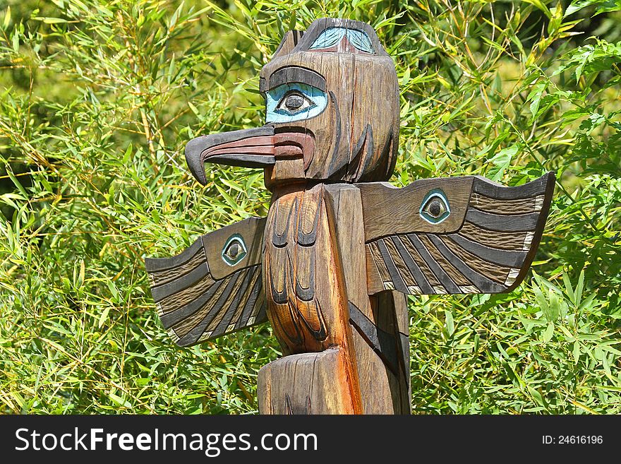 Hand Carved and Painted Wood Totem Pole With Bright Green Background