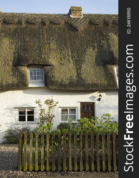 Traditional home nestled behind garden fence in in small village in England. Traditional home nestled behind garden fence in in small village in England