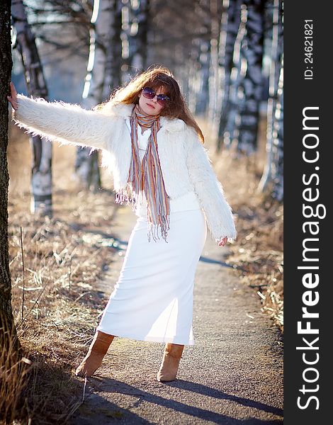 The beautiful girl in dark glasses in white clothes against birches