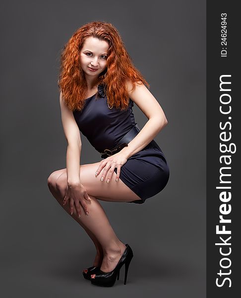 Redhead young girl in dark blue dress posing in studio. Redhead young girl in dark blue dress posing in studio