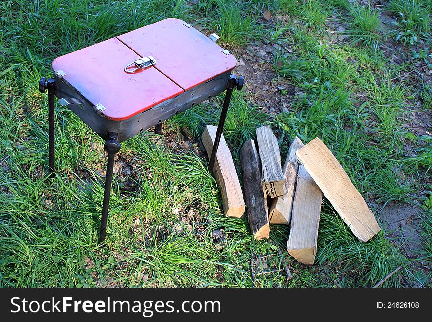 Barbecue and wood on the green grass in the summer