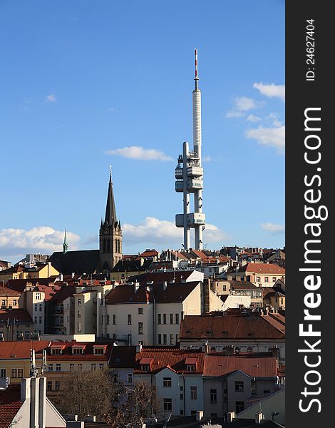 Prague's zizkov transmitter, detail on the church roof and prague, prague houses in the background with a blue sky, blue sky with white clouds above prague, summer day in the streets of prague