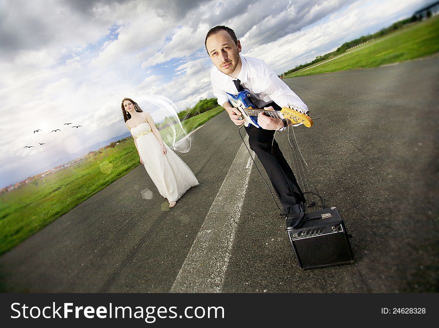 Young couple before wedding sitting on the road with a guitar