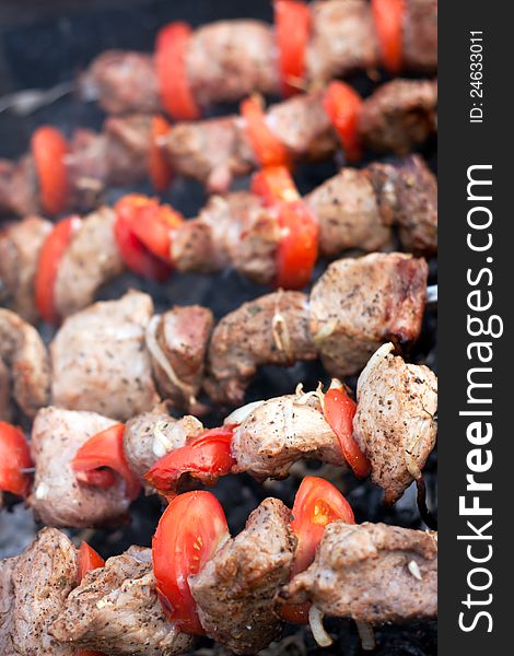 Pieces of meat and tomatoes on the grill close up. Pieces of meat and tomatoes on the grill close up.