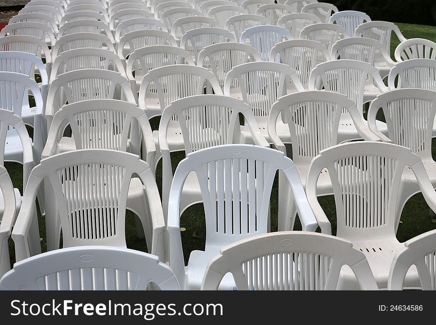 Rows of empty white plastic chairs at outdoor venue. Rows of empty white plastic chairs at outdoor venue