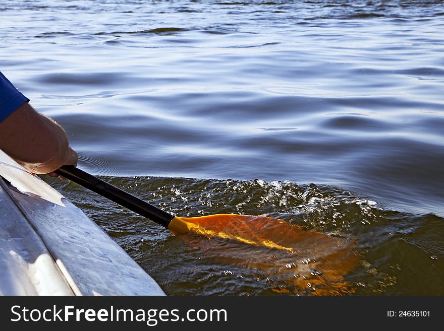 Kayak paddle on side of a boat at still river water. Kayak paddle on side of a boat at still river water