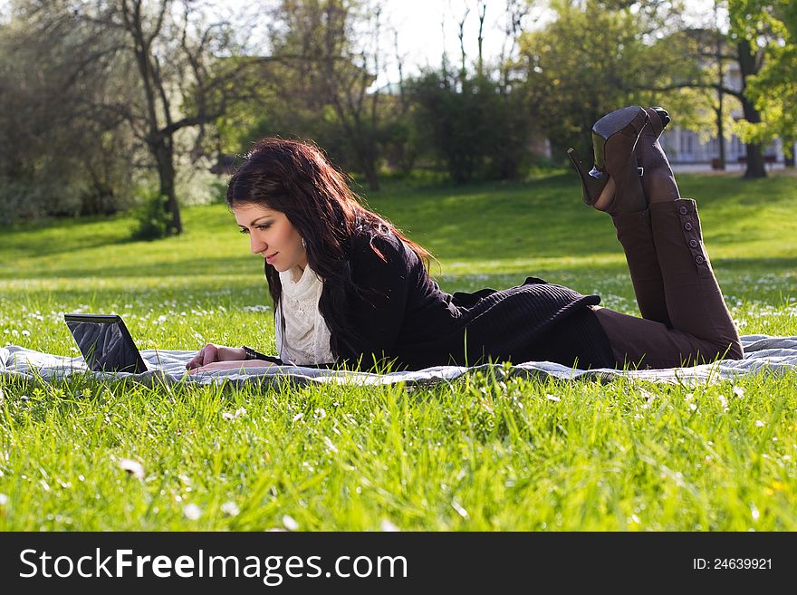 Young woman working with net-book outdoors in park on grass. Young woman working with net-book outdoors in park on grass