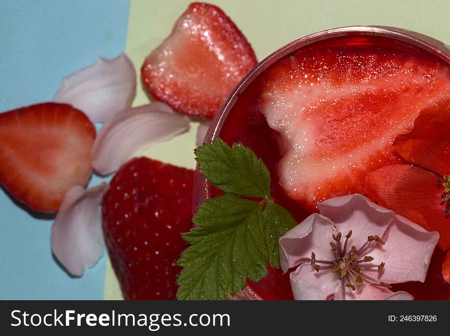 close-up and focus on a glass of strawberry juice with deokaricoja strawberry and flower head red and white under a glass of straw
