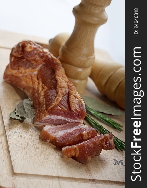 Pieces of bacon with herbs on the wooden board. Pieces of bacon with herbs on the wooden board