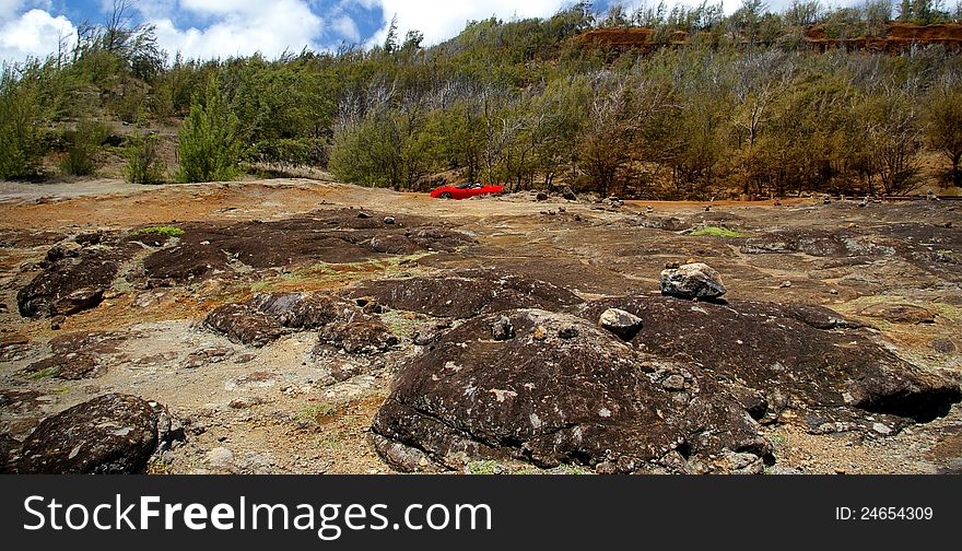 A red Corvette ride in a beautiful rocky mountainous area along the coastline of Maui, Hawaii. A red Corvette ride in a beautiful rocky mountainous area along the coastline of Maui, Hawaii