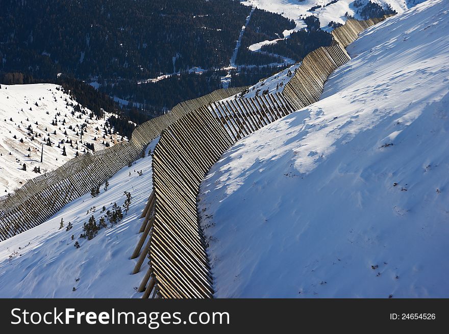 View of the valley from the mountainside with an avalanche fence