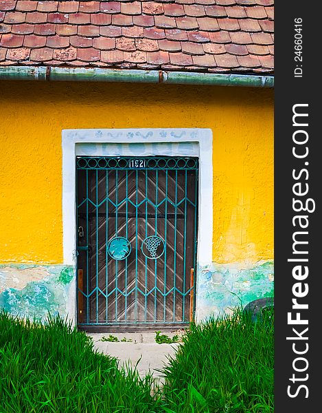 Locked door and colorful yellow wall and grass foreground