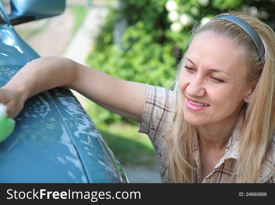 Young woman washing her car outside the house
