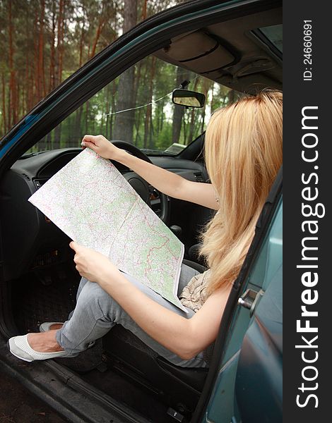 Photo of elegant woman sitting by her car and looking at map