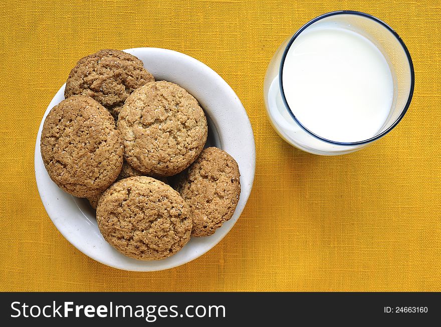 White plate with oat cookies and glass with milk