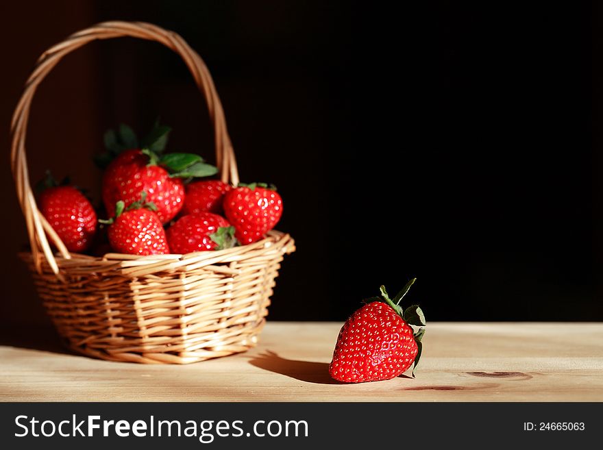 Wicker basket full of strawberries on wooden surface under sunbeam. Good background with free space for text. Wicker basket full of strawberries on wooden surface under sunbeam. Good background with free space for text