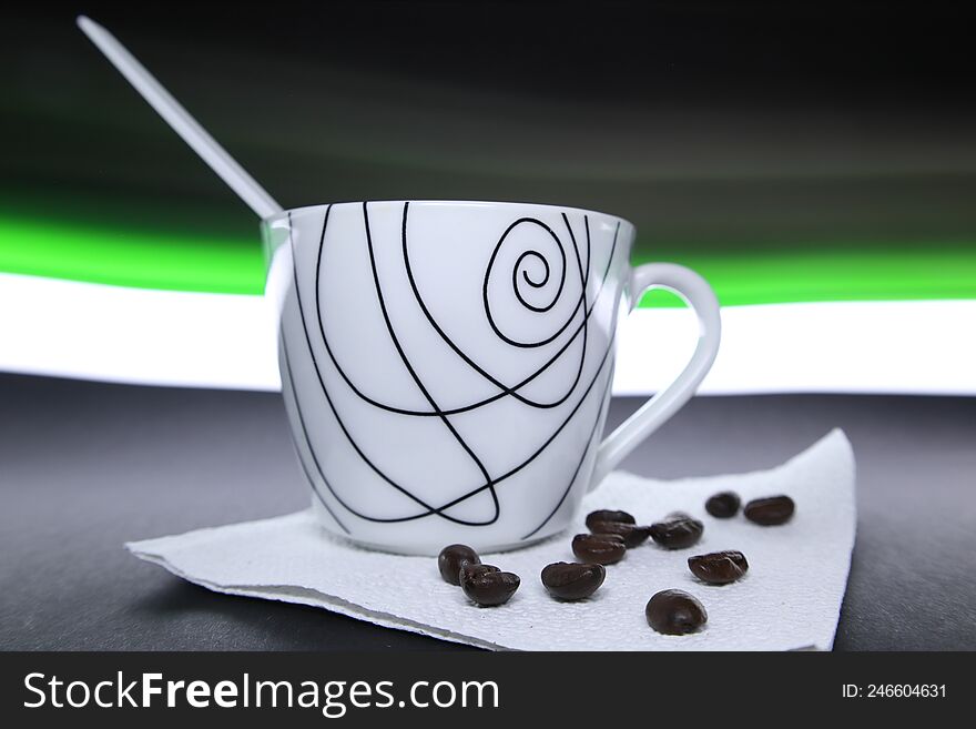 Coffee cup with beans next to it and green and white light in the background