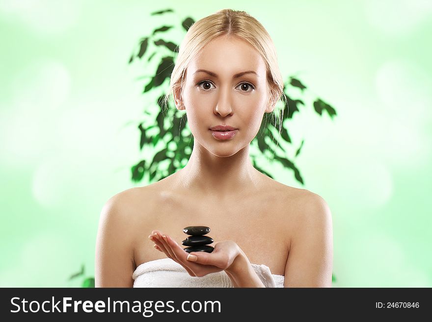 Beautiful blonde with zen stones in hand over green background