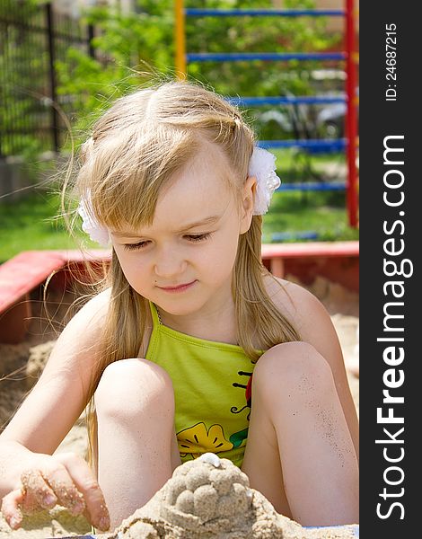 Girl Galina plays in a sandbox, does cakes.