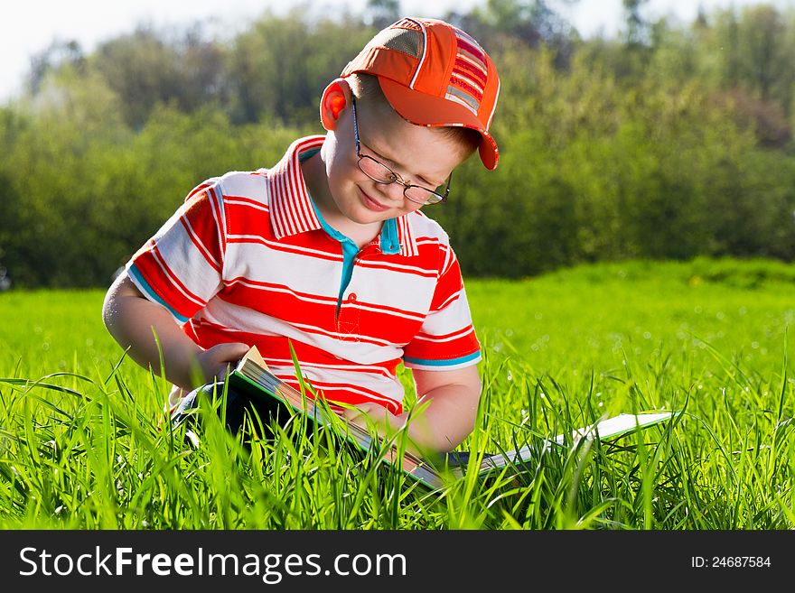 Young boy reads book in outdoor park