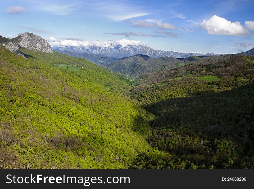 Mountains covered of lush forests seen from Piedras Luengas viewpoint on a shiny spring day with high mountains covered with snow on the background. Mountains covered of lush forests seen from Piedras Luengas viewpoint on a shiny spring day with high mountains covered with snow on the background