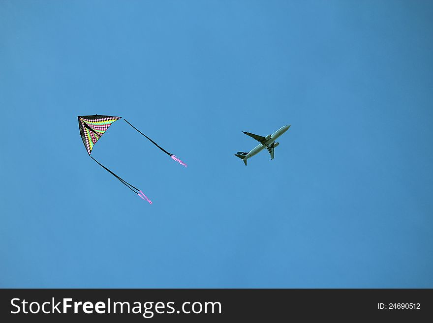 A kite and a airplane in the sky