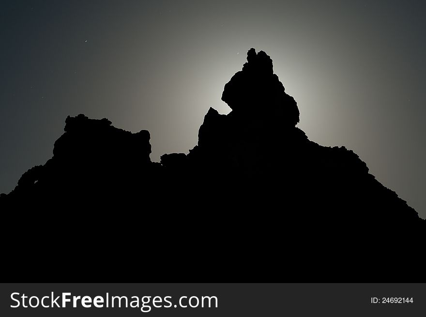 Dark Jagged Peak is Silhouetted in the moon light. Faint stars can be seen at night. Dark Jagged Peak is Silhouetted in the moon light. Faint stars can be seen at night.