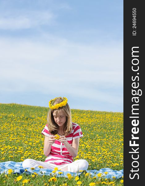 Teenage Girl Sitting On A Dandelion Field