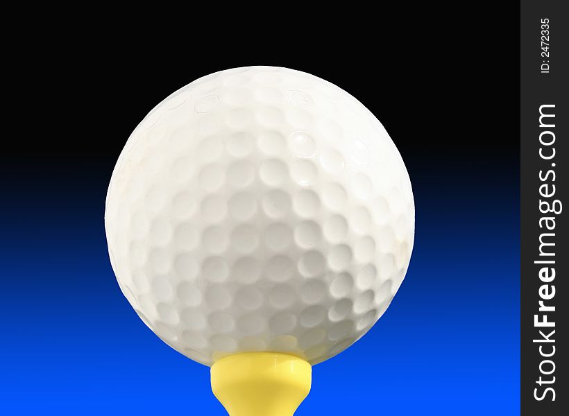 Close-up of golf ball on yellow tee against blue graduated background. Close-up of golf ball on yellow tee against blue graduated background.