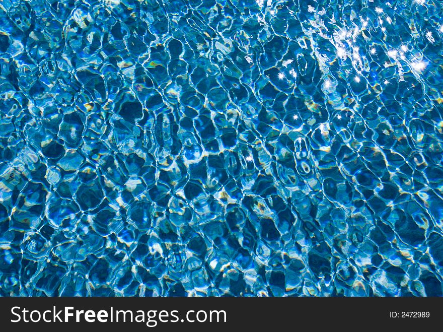 Dazzling sunlight ripples on blue water in a holiday resort swimming pool