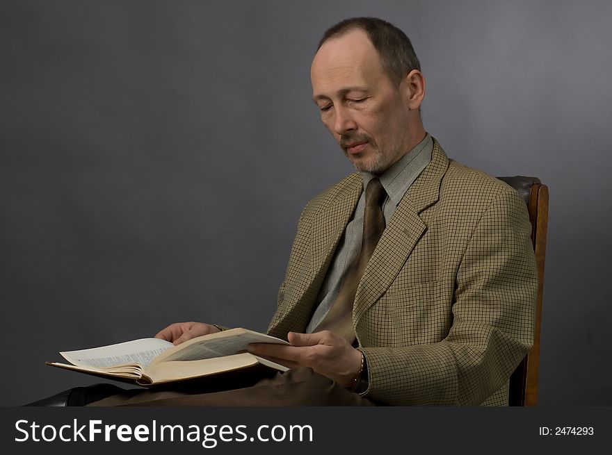 The man in a checkered suit reads the book. The man in a checkered suit reads the book