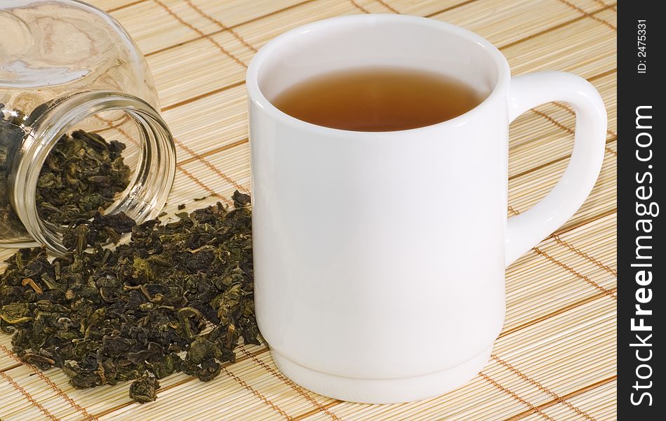 Cup of tea and tea leaves on bamboo background